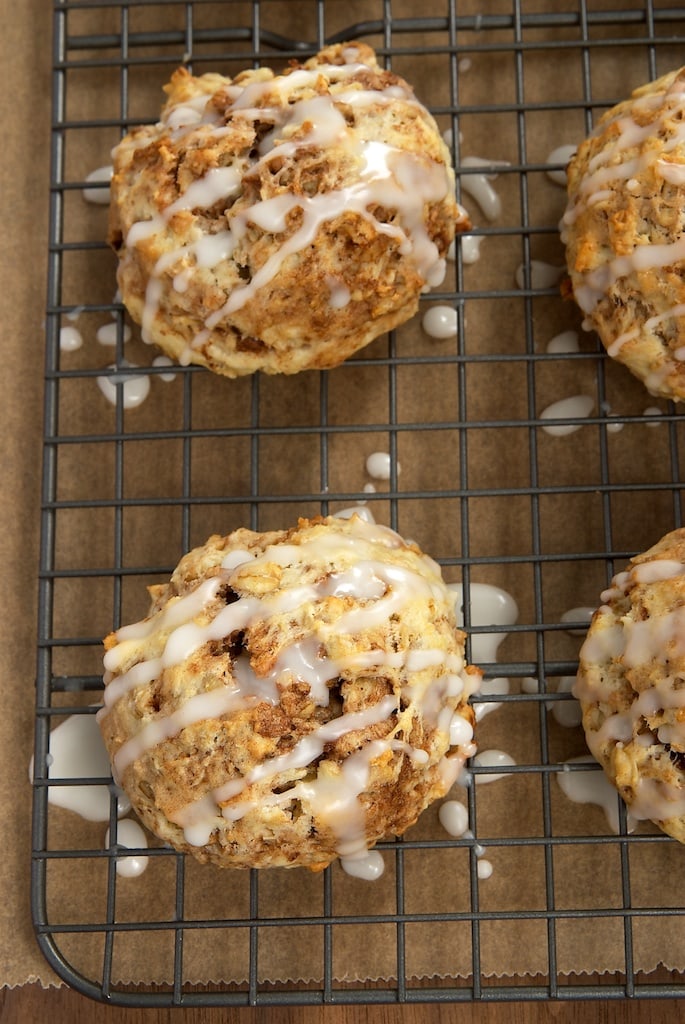Close-up shot of 2 cinnamon bun scones and glaze drizzled over them. 