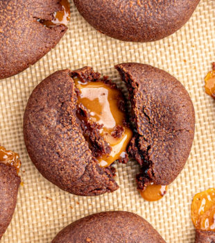 Overhead view of chocolate caramel cookie broken in half to show gooey middle