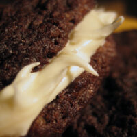 A close up of a chewy chocolate cookie with cream cheese frosting.