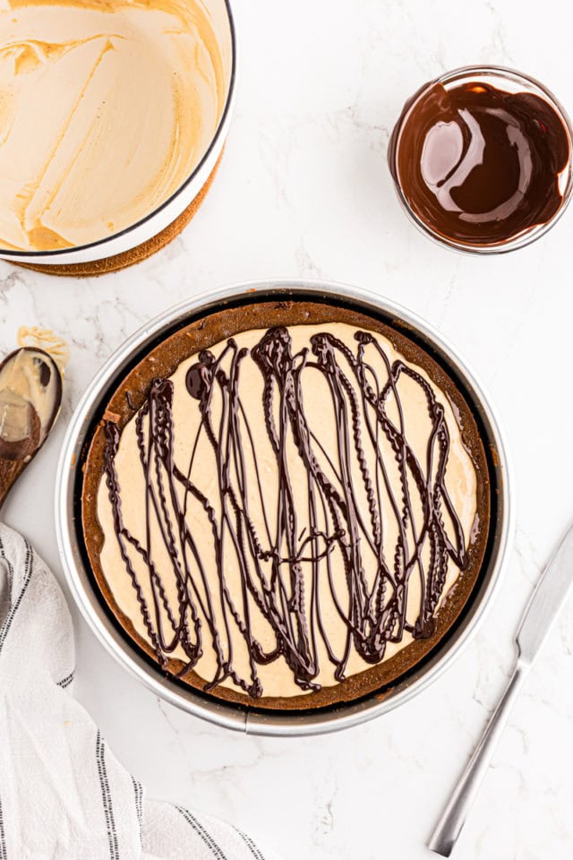 Drizzles of dark chocolate over top of chocolate peanut butter cheesecake