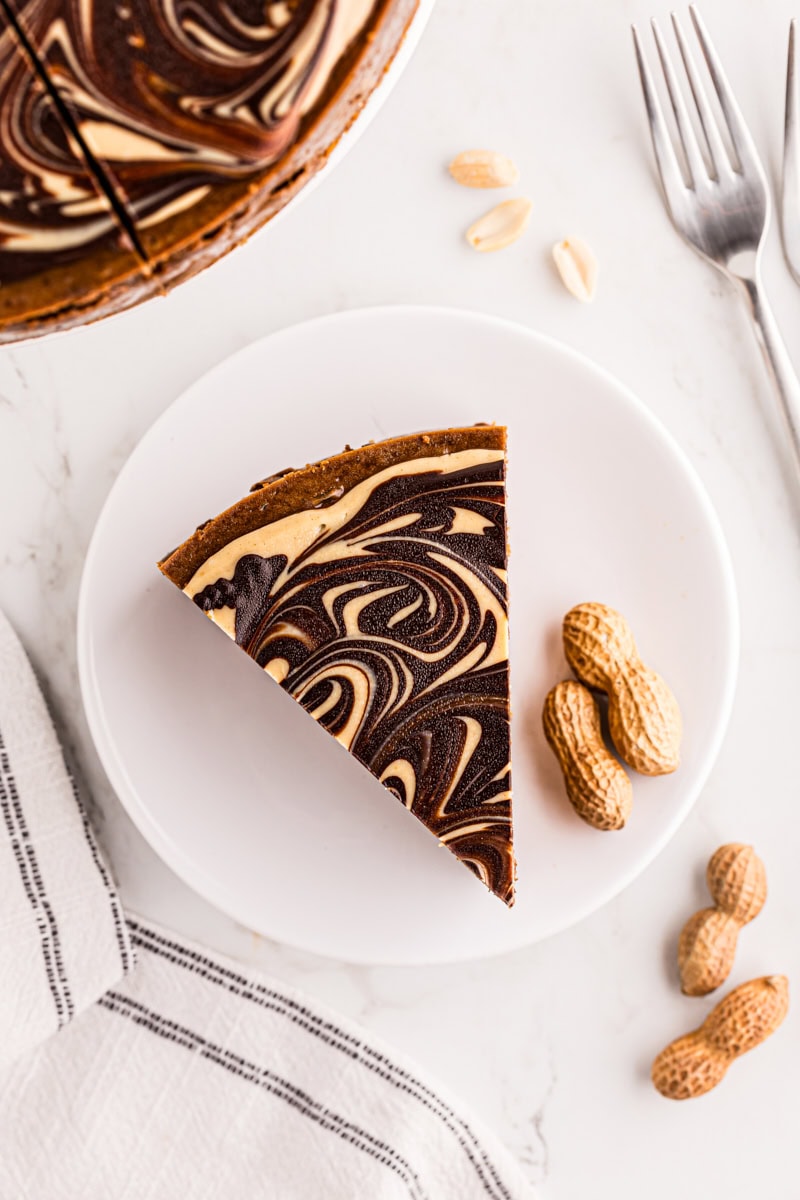 Overhead view of slice of chocolate peanut butter cheesecake on white plate