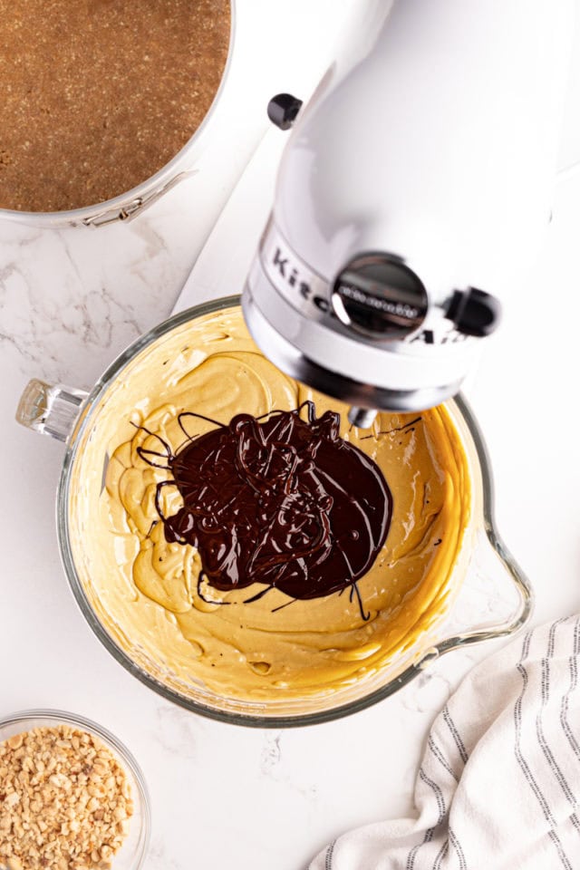 Overhead view of melted chocolate added to cheesecake filling in stand mixer
