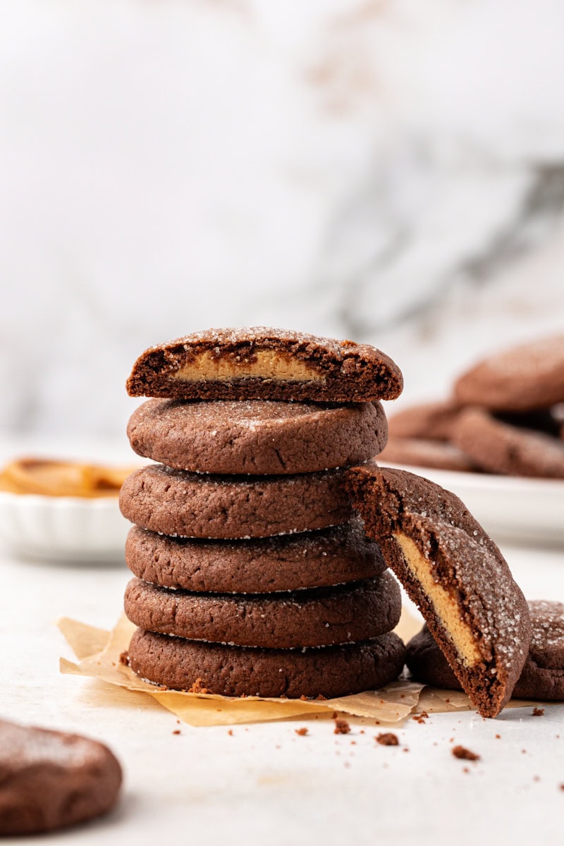 Stack of peanut butter-filled chocolate cookies, with one cookie cut in half to show filling