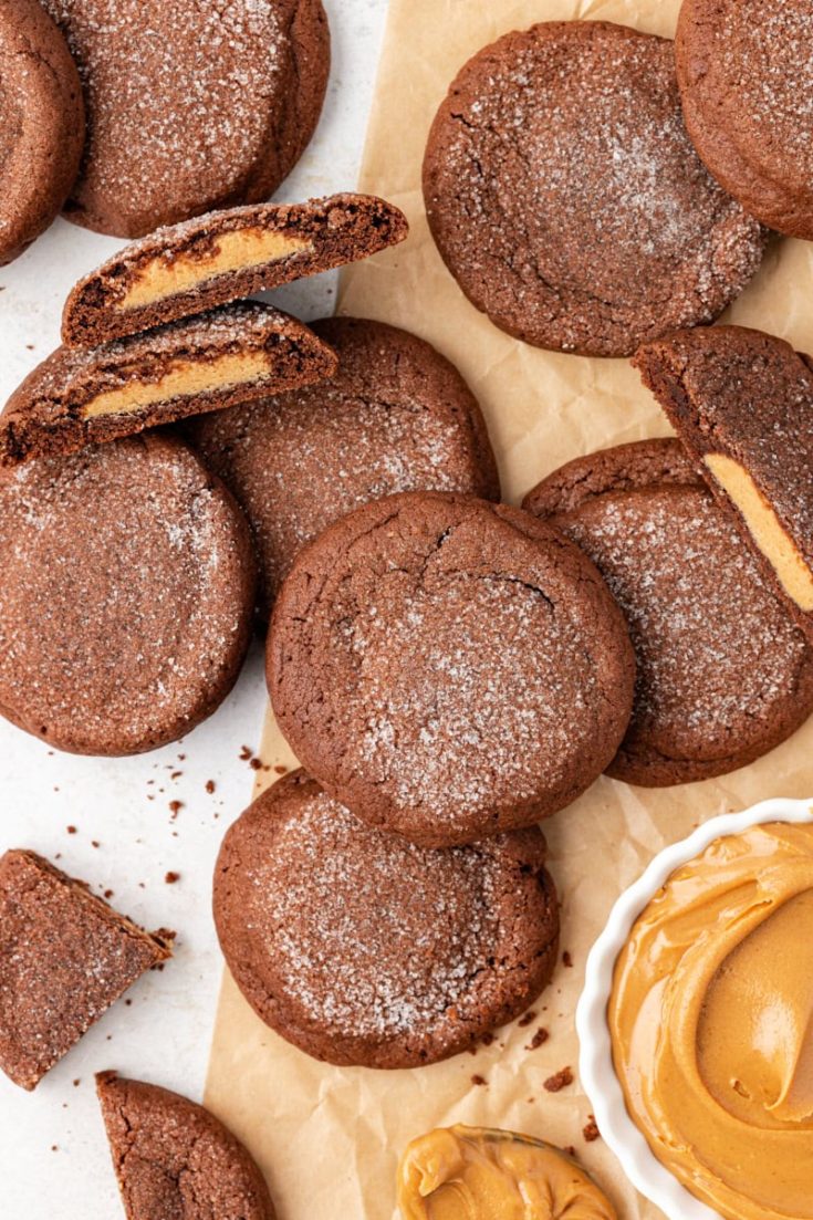 Overhead view of peanut butter-filled chocolate cookies with some cut open to show filling