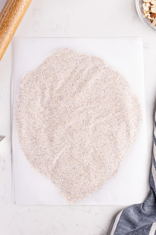 Overhead view of zimtsterne dough rolled between parchment paper