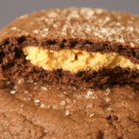 A stack of chewy chocolate munchies with the top cookie broken open to reveal a peanut butter filling.