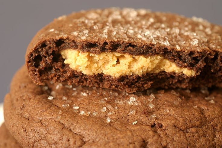 A stack of chewy chocolate munchies with the top cookie broken open to reveal a peanut butter filling.