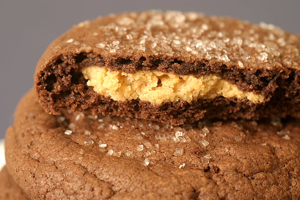 A stack of chewy chocolate munchies with the top cookie broken open to reveal a peanut butter filling.