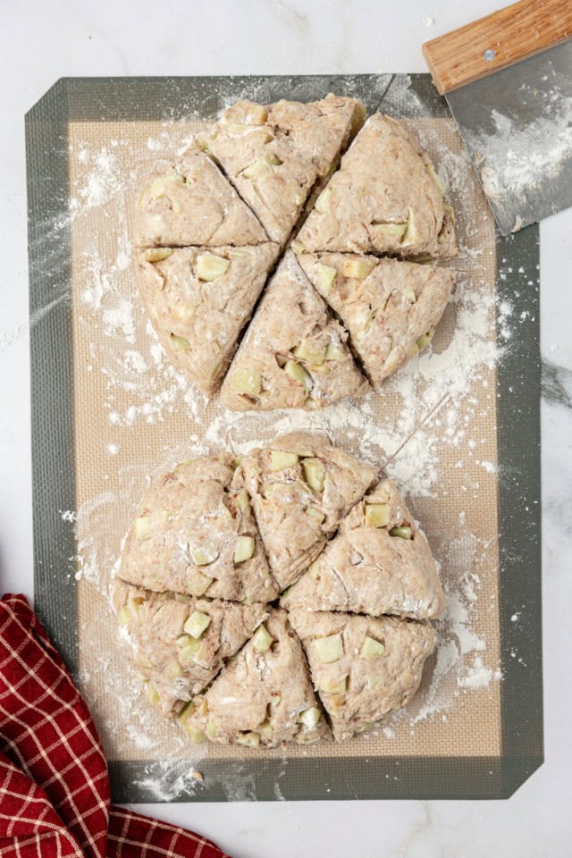 Overhead view of apple cinnamon scones on floured silpat after cutting into triangles