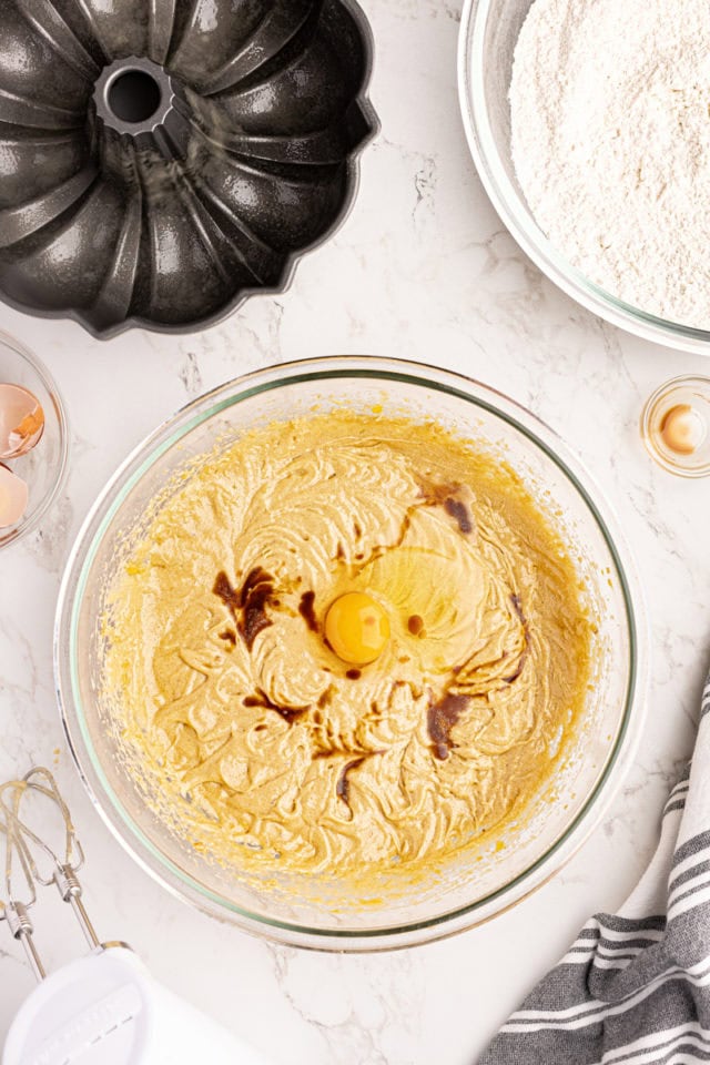 Overhead view of egg and vanilla added to bowl of wet ingredients