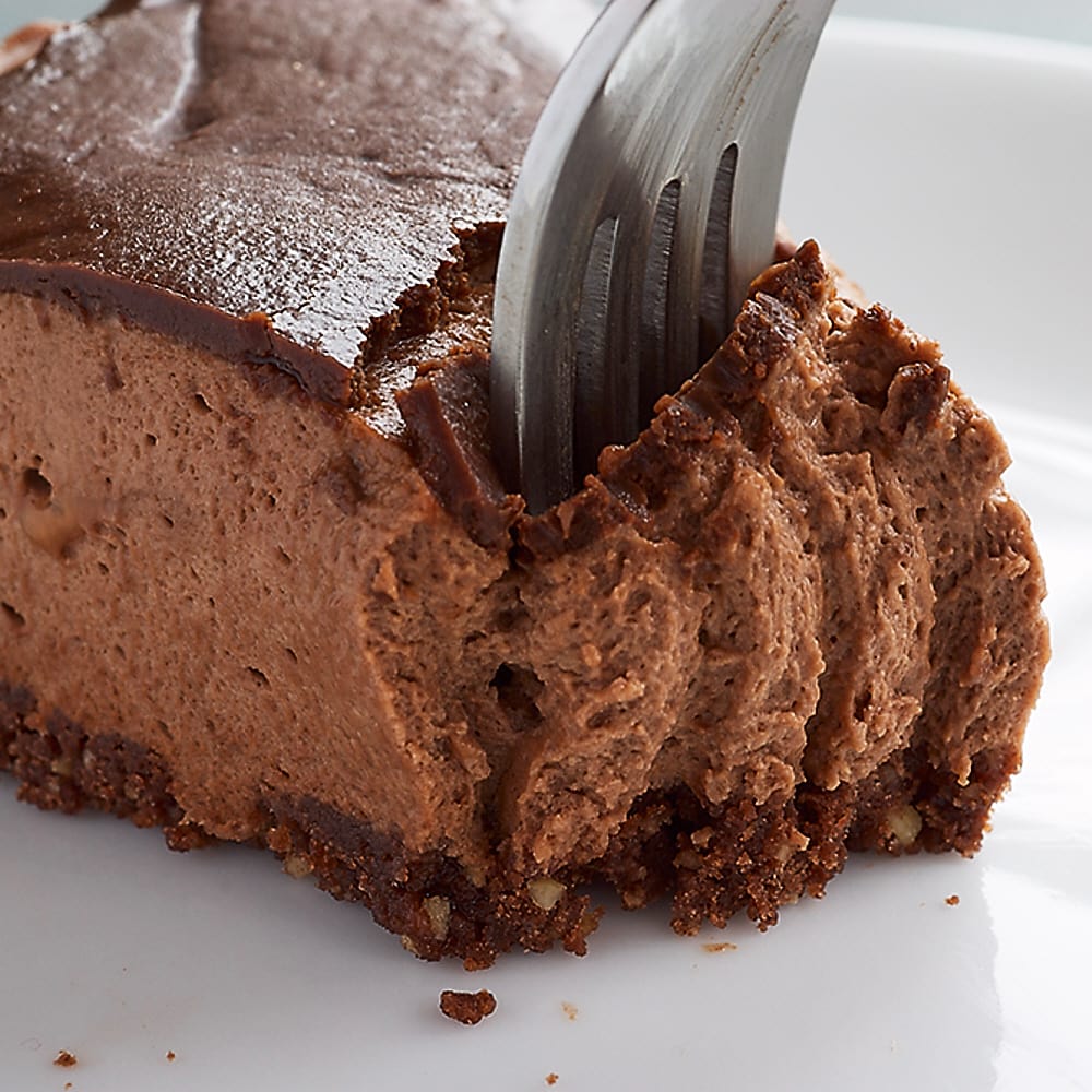 a fork digging into a slice of Chocolate-Glazed Hazelnut Mousse Cake