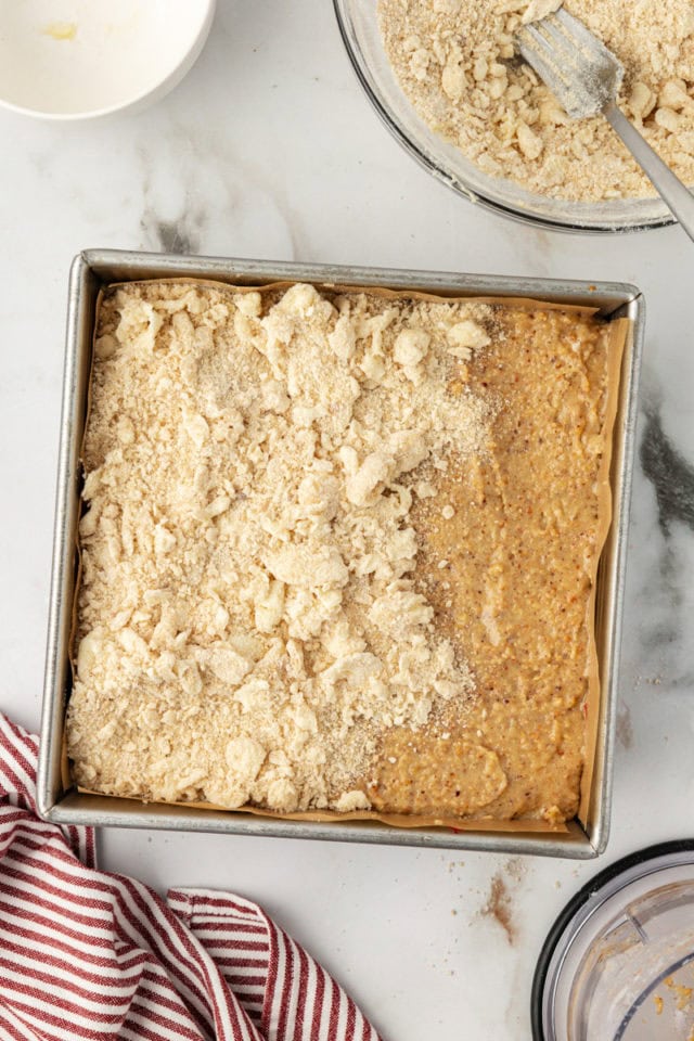 Overhead view of crumb layer being added to raspberry crumble bars