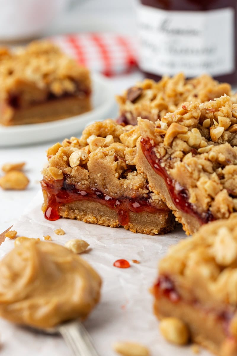 Two peanut butter and jelly bars stacked on parchment paper