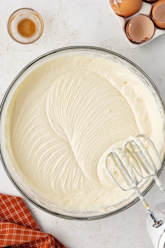 Overhead view of cheesecake filling in bowl with mixer