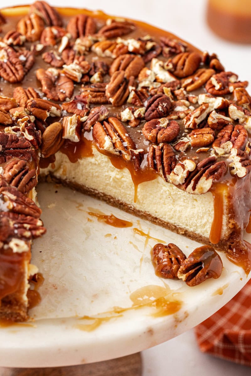 Pecan and salted caramel cheesecake on cake stand with slice removed