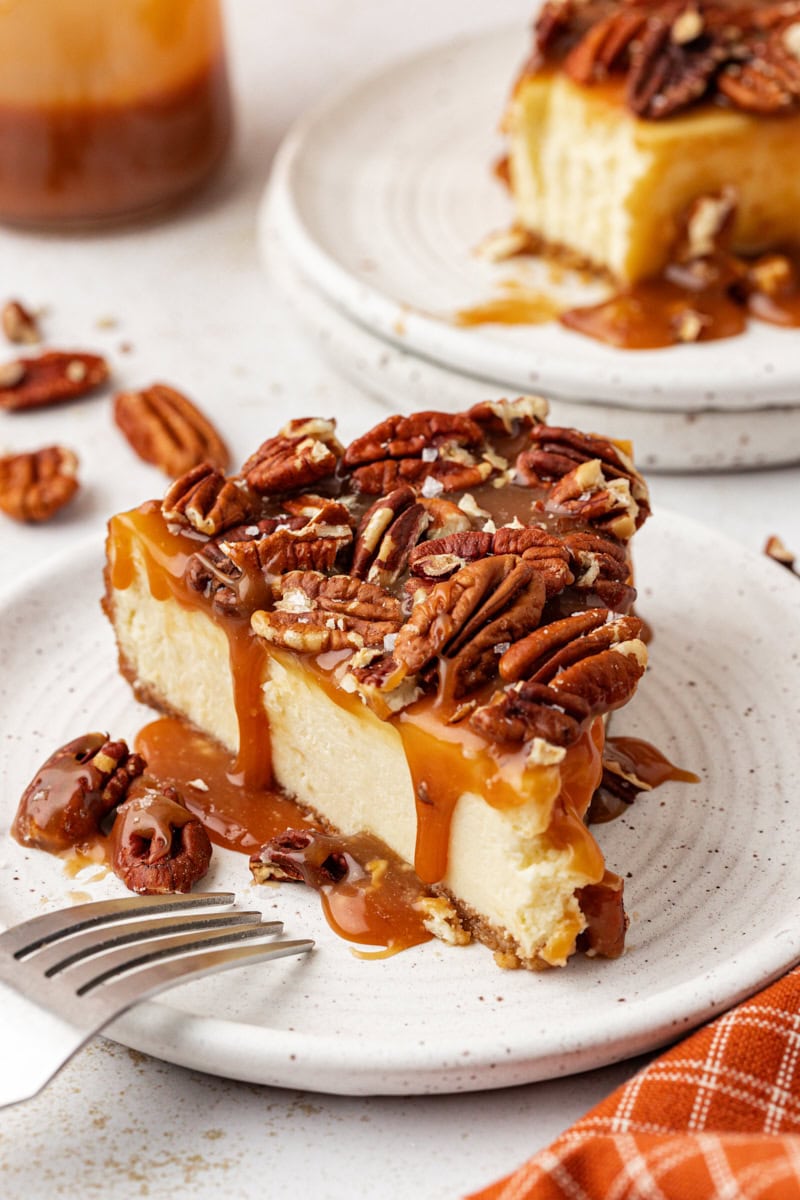 Side view of salted caramel cheesecake on plate with pecans on top