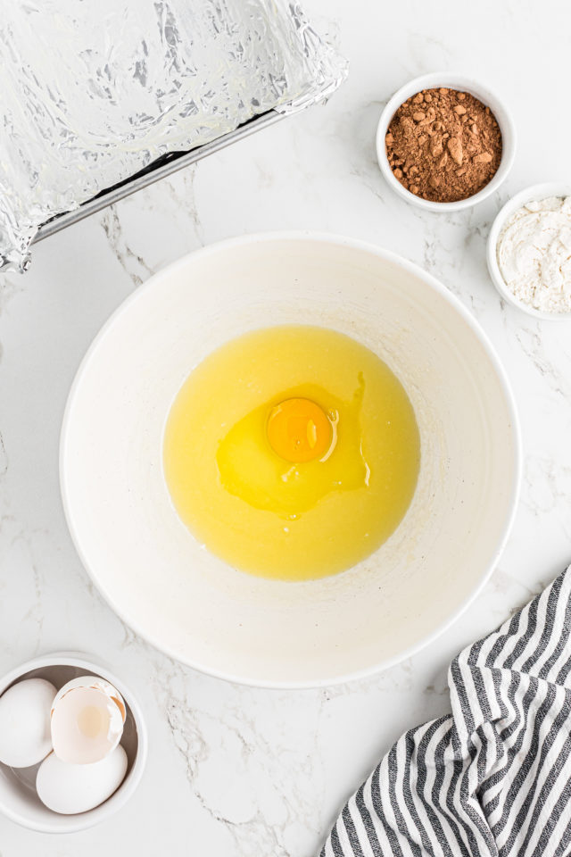Overhead view of egg and melted butter in mixing bowl