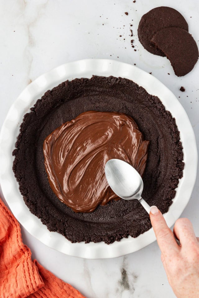 Using spoon to spread chocolate layer over crust