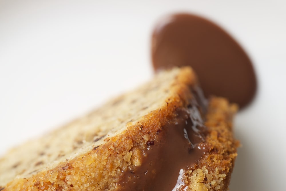 Close-up of hazelnut cake slice with chocolate syrup.