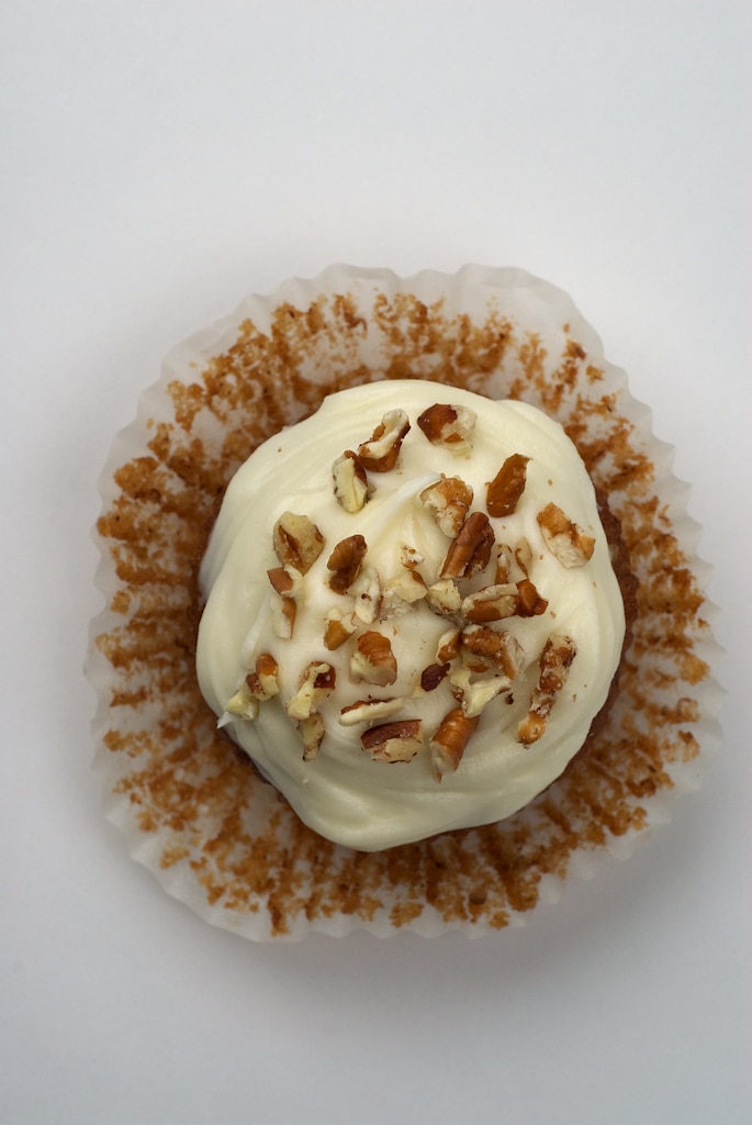 overhead view of a Hummingbird Cupcake topped with cream cheese frosting and nuts