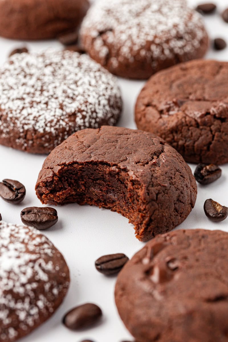 Thick and soft chocolate espresso cookies on countertop, with one bitten to show fudgy texture