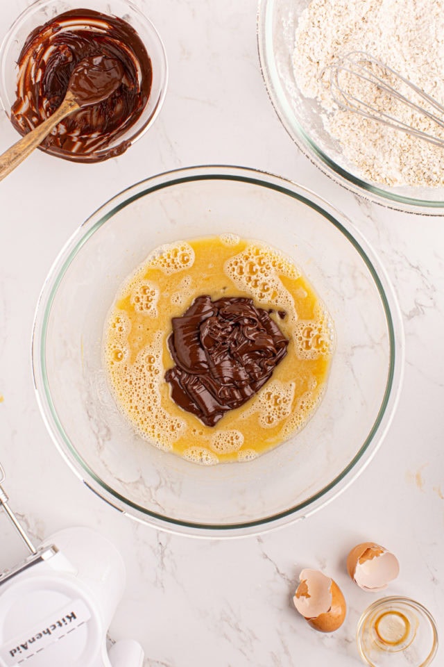 Overhead view of melted chocolate added to bowl of wet ingredients