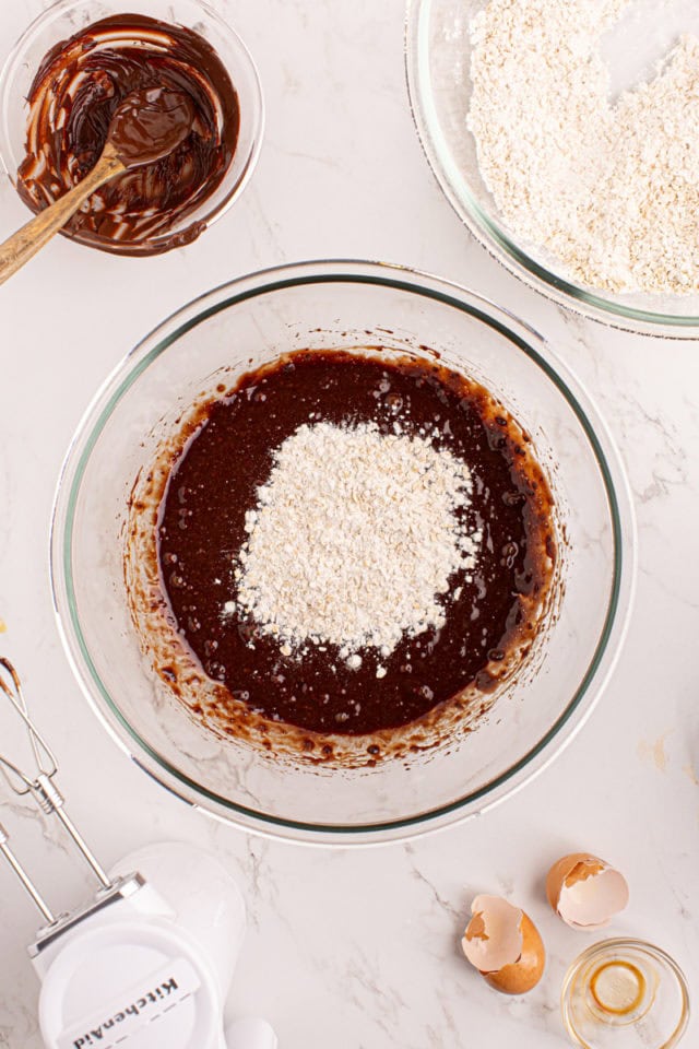 Overhead view of dry ingredients added to wet ingredients in mixing bowl