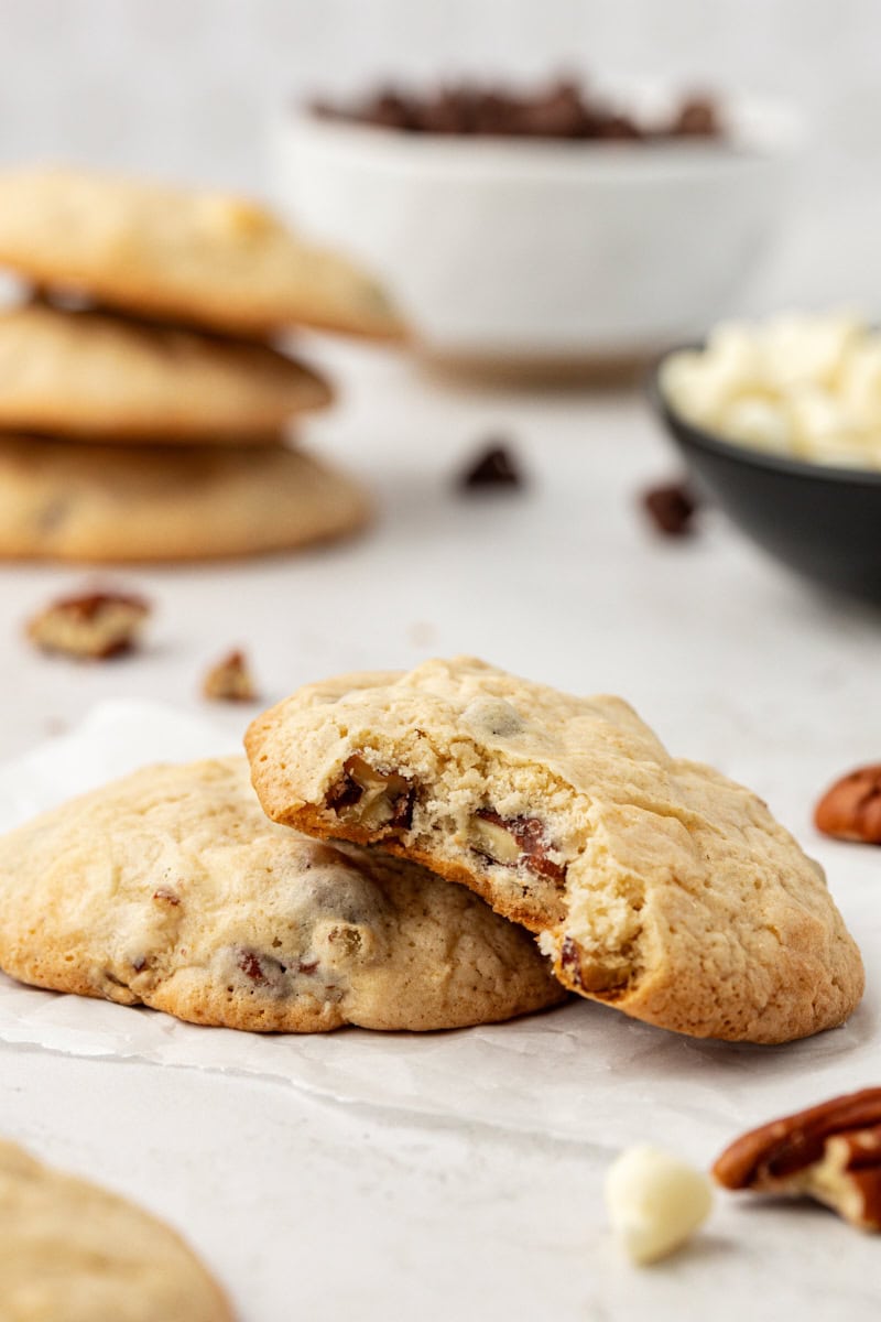 Two black and white chocolate chip cookies with top cookie bitten to show light crumb