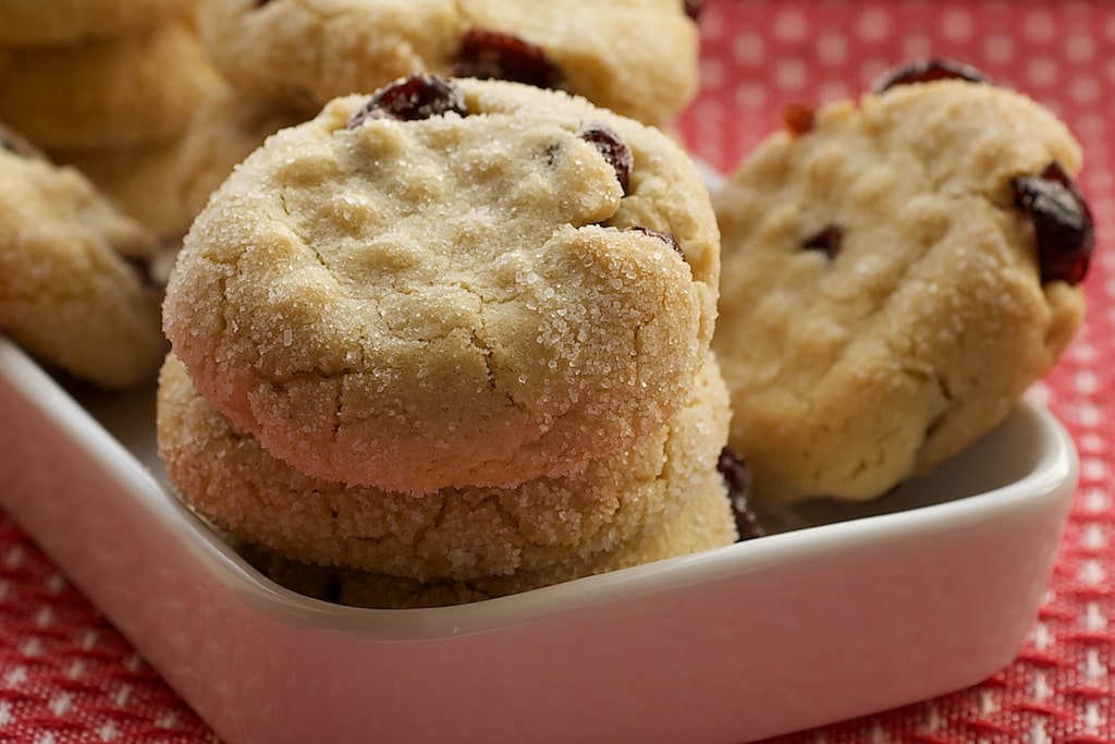 Macadamia Butter Cookies with Dried Cranberries stacked in a white serving dish