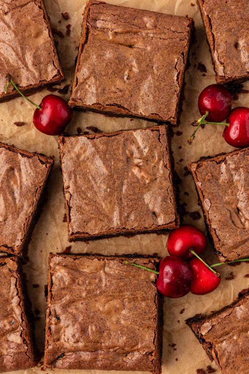 Dark chocolate sour cherry brownies arranged on parchment paper