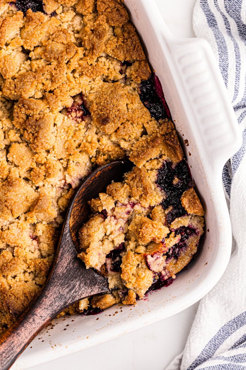 Overhead view of mixed berry cobbler in baking dish with wooden spoon
