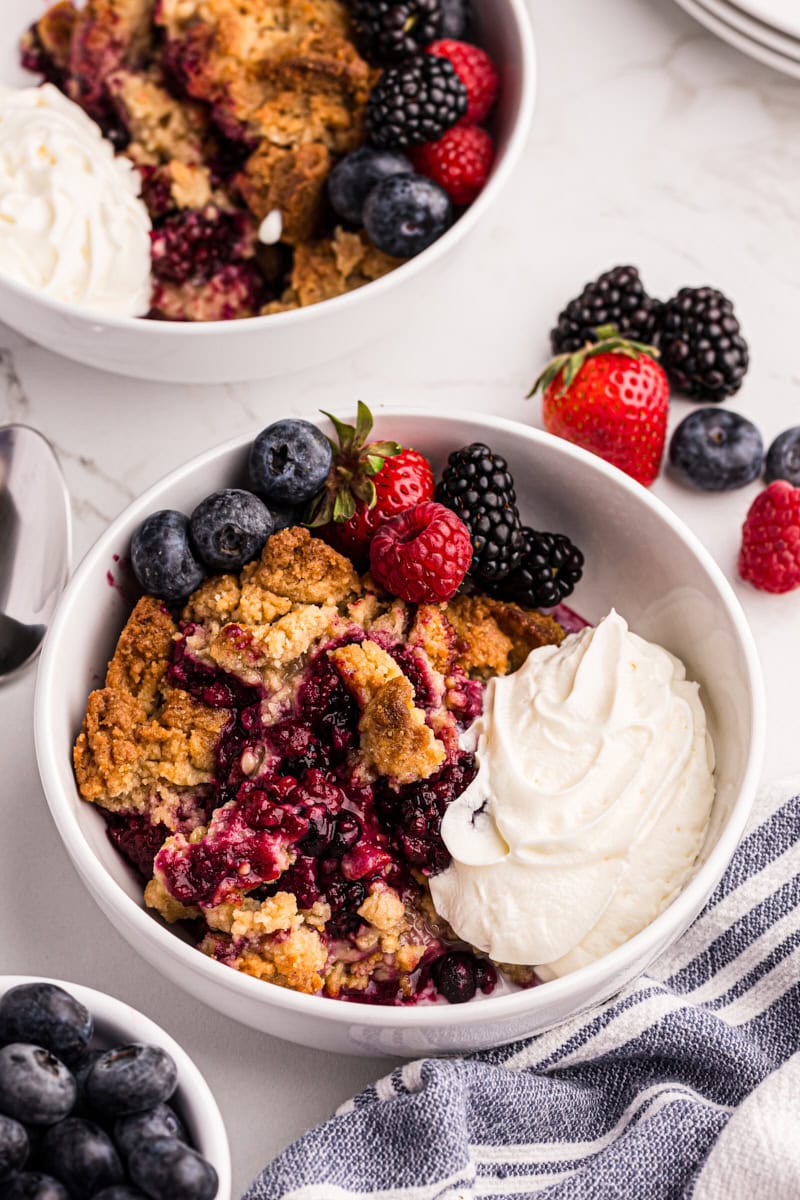 Overhead view of mixed berry cobbler in bowls with whipped cream