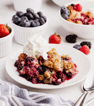 Mixed berry cobbler on plate with whipped cream