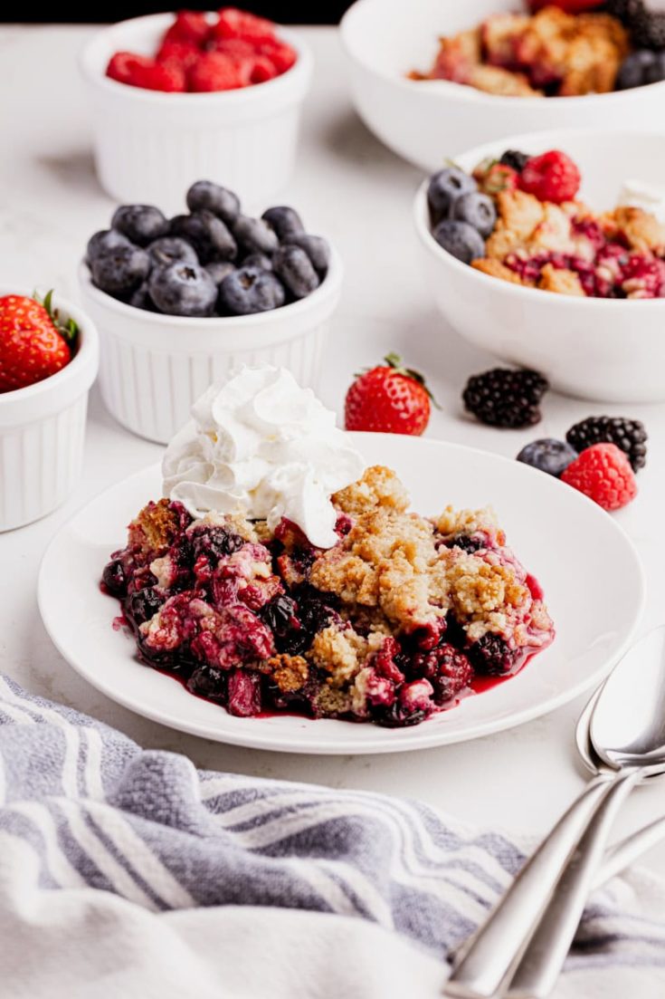 Mixed berry cobbler on plate with whipped cream