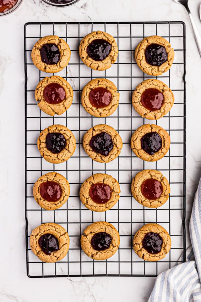 Overhead view of peanut butter and jelly thumbprint cookies on wire rack