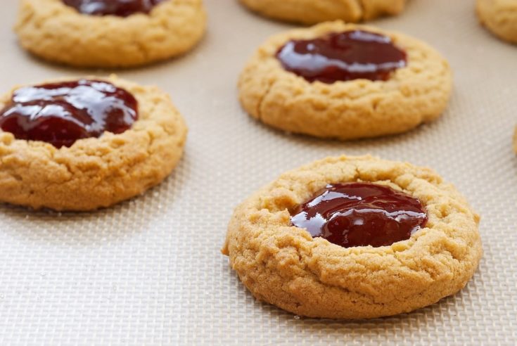 Peanut butter and jelly thumbprint cookies in rows.