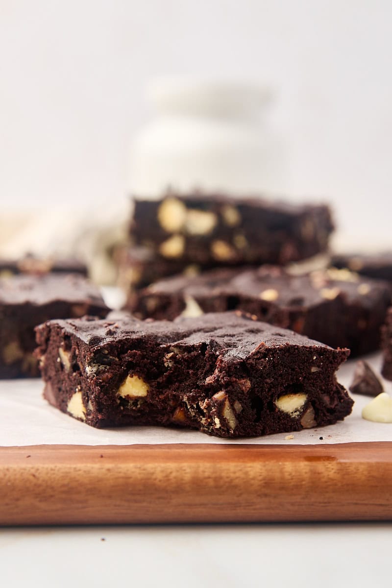 Bitten triple chocolate brownie on cutting board