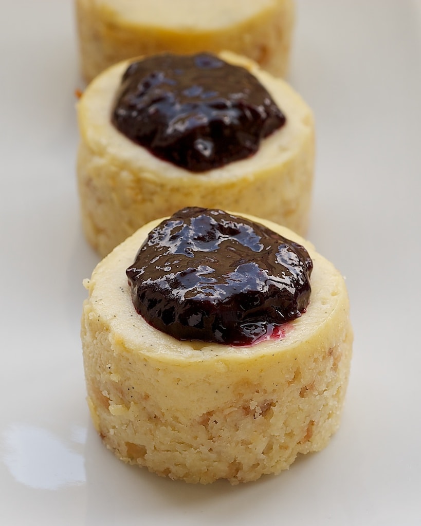 Vanilla Bean Mini Cheesecakes feature a toasted coconut crust, sweet, vanilla cheesecake, and a fresh blueberry sauce. - Bake or Break