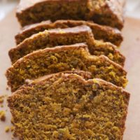 Sliced Pumpkin Pecan Bread on a wooden cutting board.