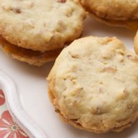 Almond and apricot sandwich cookies on a plate.
