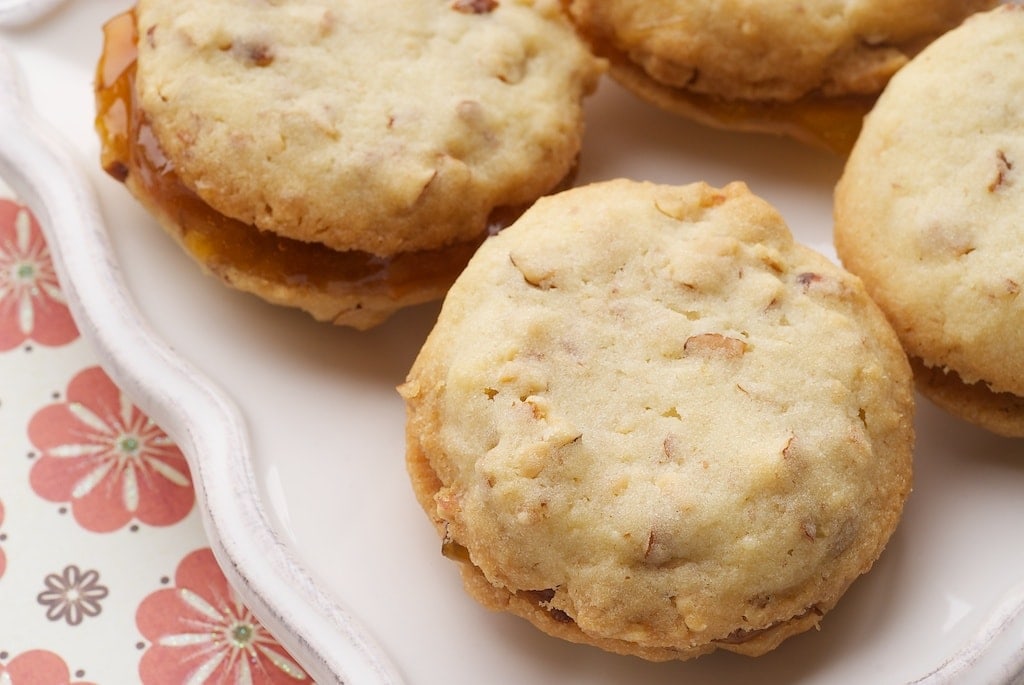 Almond and apricot sandwich cookies on a plate.