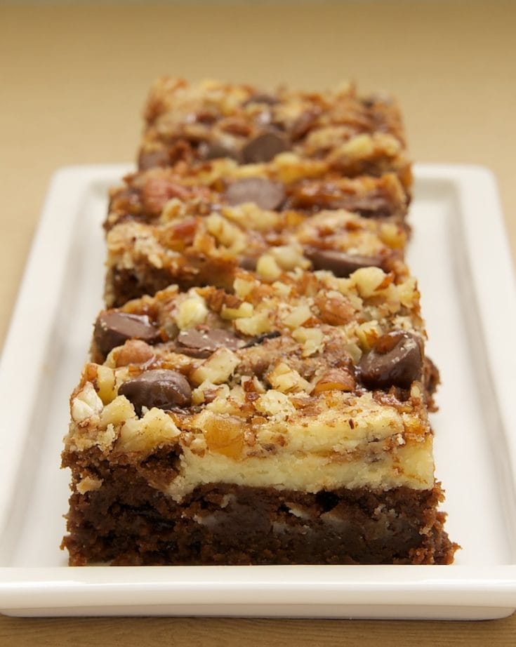 3 cream cheese brownies with toffee and pecans lined up on rectangular tray