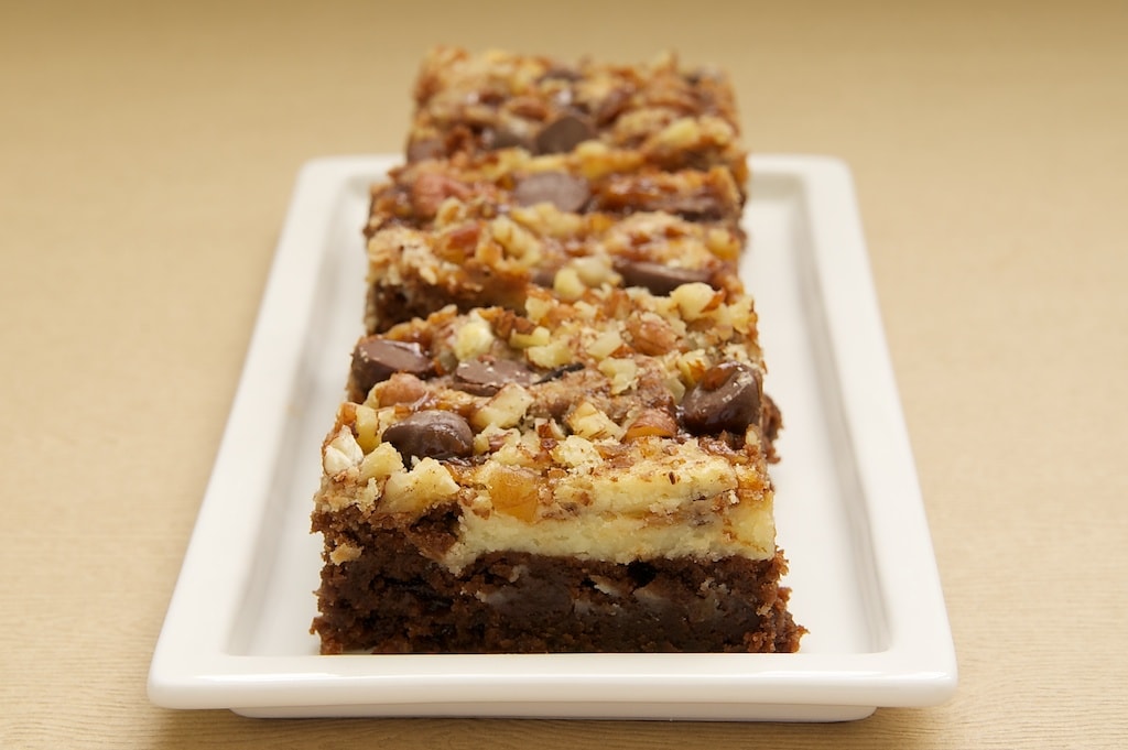 Closeup of cream cheese brownies with toffee and pecans on narrow rectangular platter