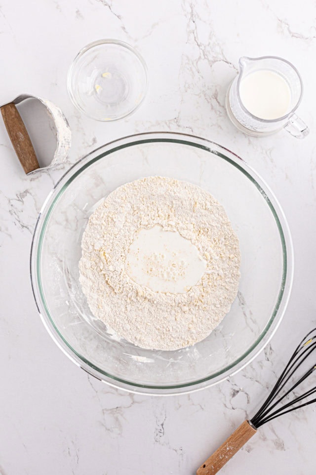 Overhead view of buttermilk poured into dry ingredients for biscuits