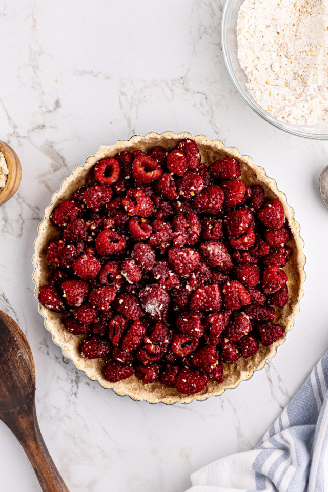 Overhead view of raspberries added to almond tart crust