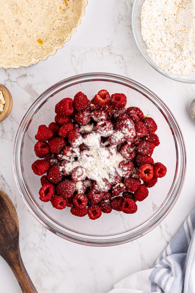 Overhead view of dry ingredients added to raspberries in bowl