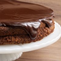 Flourless Chocolate Cake with Chocolate Ganache on a white cake stand