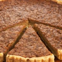 Caramel chess tart on cutting board with 3 slices cut and pulled away