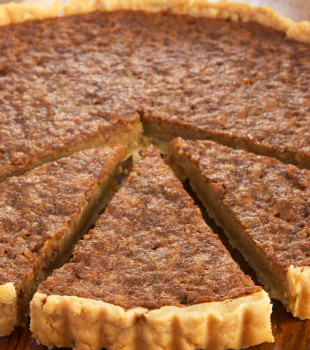 Caramel chess tart on cutting board with 3 slices cut and pulled away