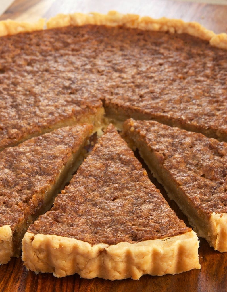 Caramel chess tart on cutting board with 3 slices cut and pulled away